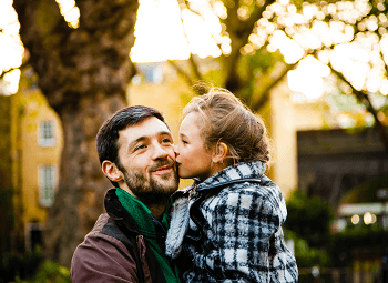 Dad holding his kid outside both are dressed for fall weather