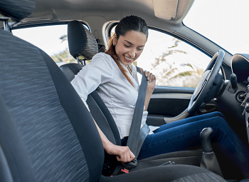 young woman buckling herself into the driver seat of a car