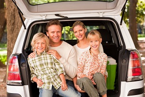 family sitting in the back on an SUV smiling at camera