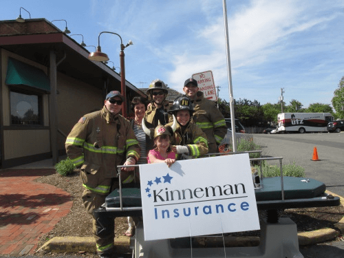 Fairfax County Firefighters holding a Kinneman Insurance sign