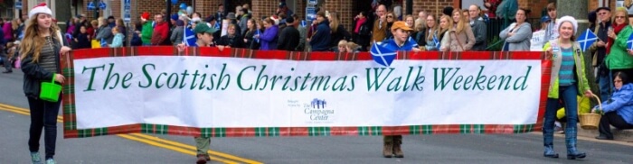 The Scottish Christmas Walk Weekend banner being held by several people during the parade