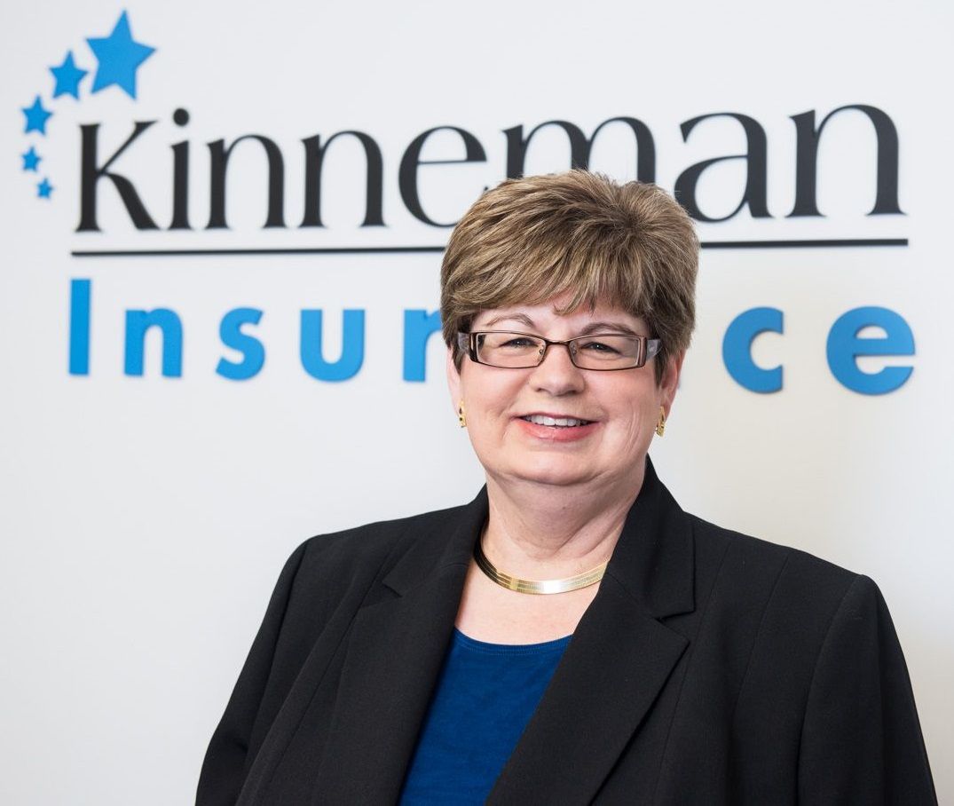 Virginia Kinneman standing in front of company logo